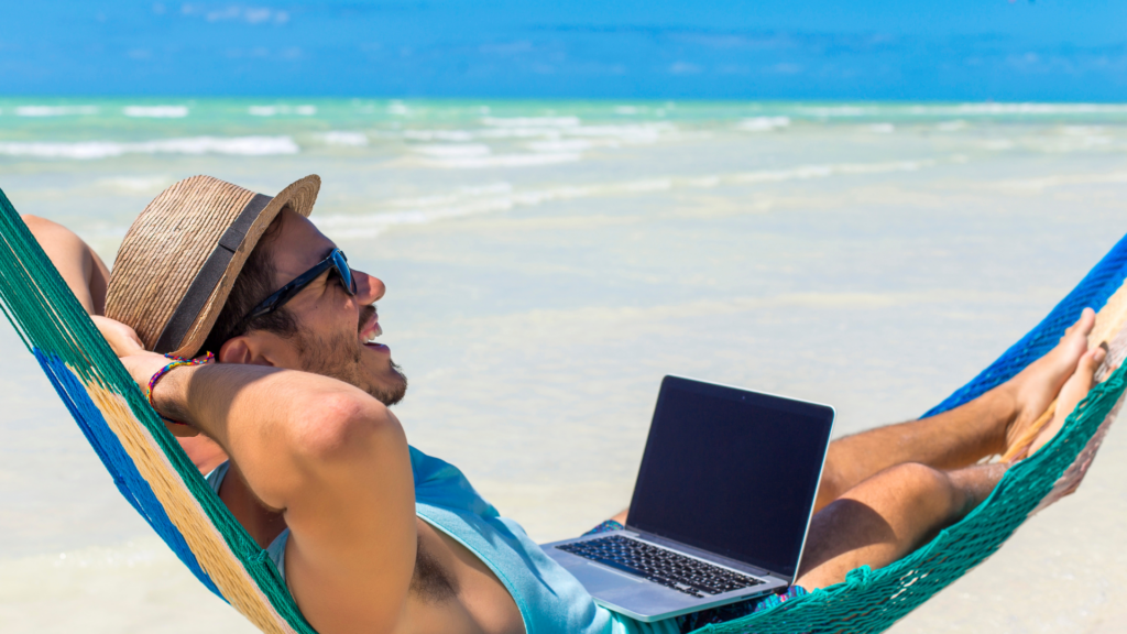 A person holding a laptop on the beach hammock, living in bali as a digital nomad