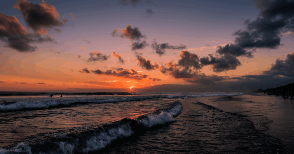 Sunset over the ocean near luxury bali villas in seminyak with waves and dramatic clouds