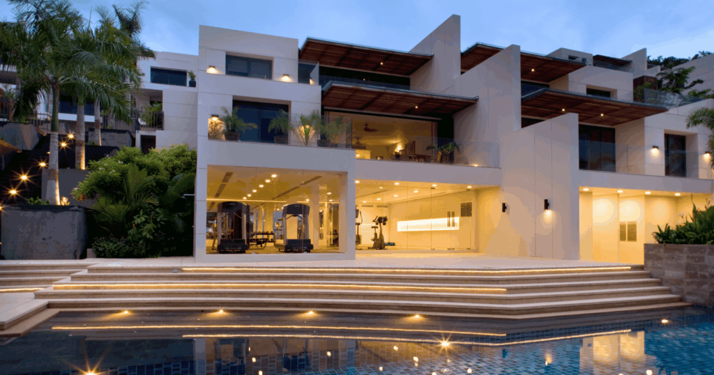 Contemporary multi-level villa with pool and glass-front gym at dusk